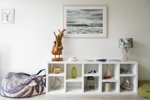 un estante blanco con jarrones y una foto en la pared en Seasky, en Praa Sands