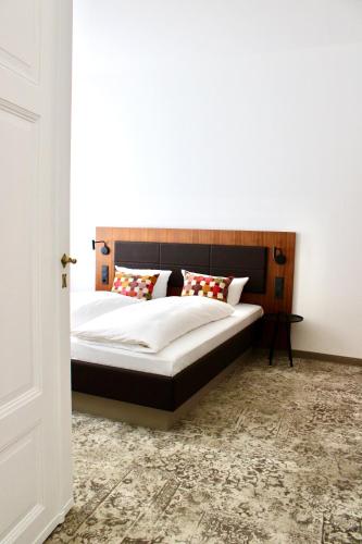 a bedroom with a bed with white sheets and red pillows at Hotel Alma Am Anger in Erfurt