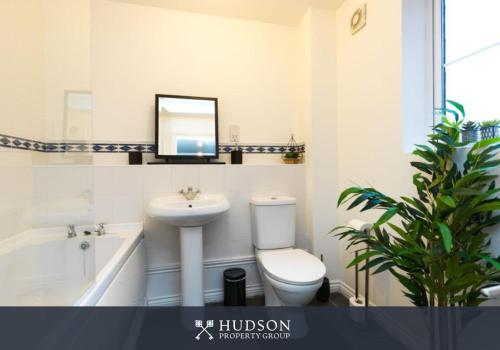 a bathroom with a toilet and a sink and a mirror at Telford 2-Bedroom Apartment in Telford