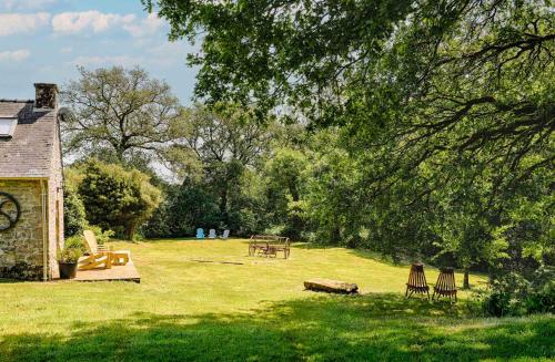 a park with chairs and a picnic table in the grass at FORET TOTEM - Hébergements nature et bien-être en pleine forêt in Persquen