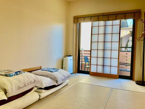 a bedroom with two beds and a sliding glass door at Ducale Garden Hotel Kujukuri in Kujukuri