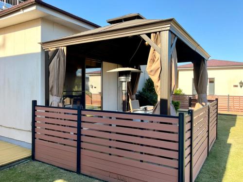 a wooden deck with an open canopy on top of it at Ducale Garden Hotel Kujukuri in Kujukuri