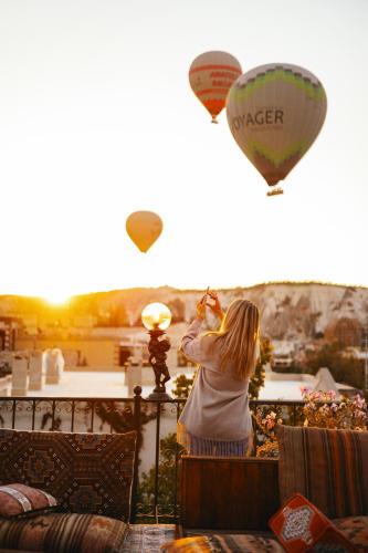 a woman taking a picture of a hot air balloon at Goreme Valley Cave House in Göreme