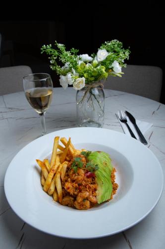a plate of food with french fries and a glass of wine at Hotel Grand Park in Bogotá