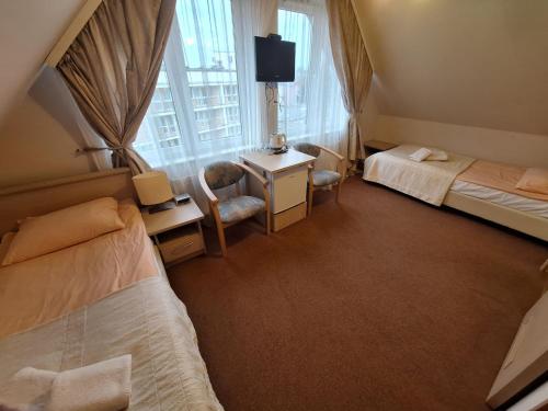 a bedroom with two beds and a desk and a tv at Politechnika Warszawska Ośrodek Wypoczynkowy in Sarbinowo