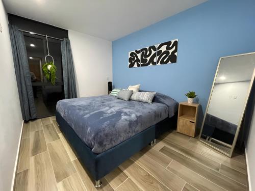 a bedroom with a blue bed and a mirror at Depa Familiar con cochera 6 min Centro Médico y Catedral in Guadalajara
