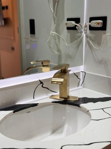 a bathroom sink with a gold faucet in front of a mirror at Hotel Boutique Las Mesetas in San Pedro Sula