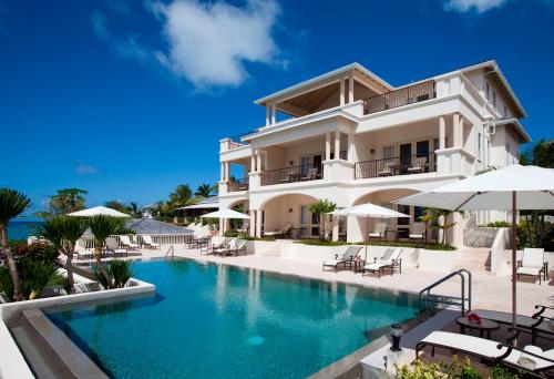 a large white building with a swimming pool at The Cove Suites at Blue Waters in Saint Johnʼs