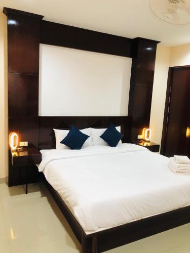 a bedroom with a large white bed with blue pillows at Royal Star Suites pattaya in Pattaya South