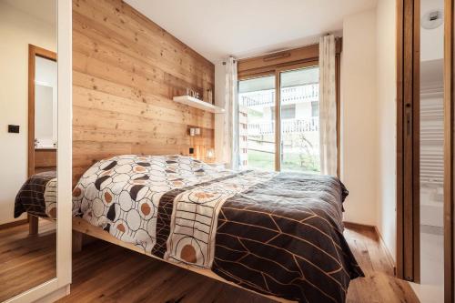 une chambre avec un lit et un mur en bois dans l'établissement Apartment Nid des Neiges - Perfect for families, à Combloux
