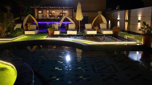 a swimming pool at night with chairs and tables at La Zona Continental Hotel in Dubai