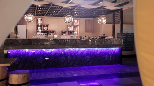 a bar with purple lighting in a room at La Zona Continental Hotel in Dubai