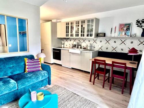 a living room with a blue couch and a kitchen at Magnifique logement plein centre face aux pistes in Auron