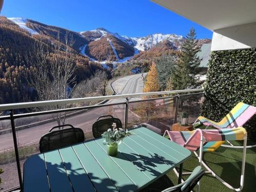 a table on a balcony with a view of a mountain at Magnifique logement plein centre face aux pistes in Auron