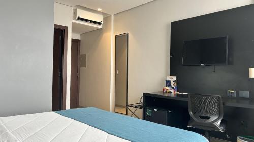 a bedroom with a bed and a desk and a tv at Comfort Hotel & Suítes Rondonópolis in Rondonópolis