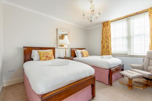 a bedroom with two beds and a chair and a chandelier at The Windmill Room - 1 min to Old Course in St. Andrews