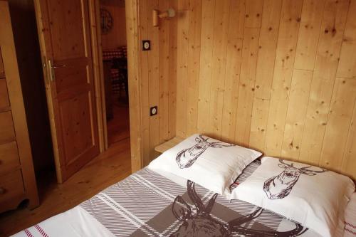 a bed in a room with wooden walls and wood floors at Etangs du Moulin in Suzy