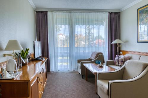 a hotel room with a couch and a table and a window at Ensana Thermal Hévíz in Hévíz
