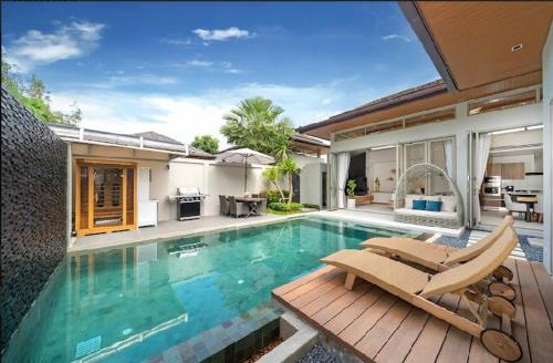 a swimming pool with chairs and a house at Villa private swimming pool and garden in Phuket Town