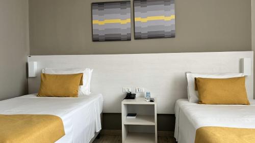 two beds with yellow pillows in a room at Comfort Hotel & Suítes Rondonópolis in Rondonópolis