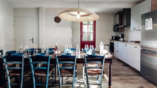 une table à manger avec des chaises bleues et un lustre dans l'établissement Maison Bleue Est 12 personnes, à Saint-Julien-en-Born