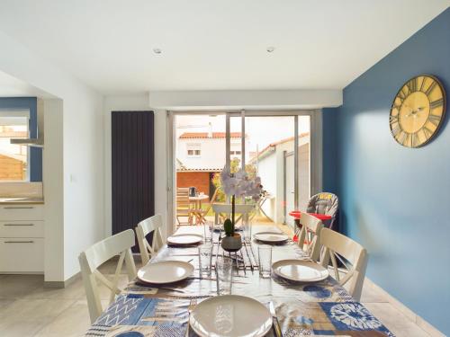 une salle à manger avec une table et une horloge au mur dans l'établissement À 15min à pied de la plage, maison pour 6, à Les Sables-dʼOlonne