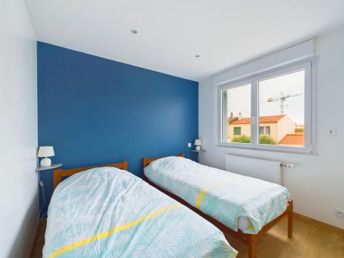- 2 lits dans une chambre avec un mur bleu dans l'établissement À 15min à pied de la plage, maison pour 6, à Les Sables-dʼOlonne