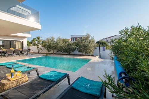 a swimming pool with a table and chairs next to a house at Villa Ajlin mit privatem beheizbarem Pool in Medulin