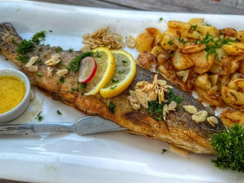 a white plate with a fish with lemon slices and shrimp at Hotel | Restaurant | Forellenzucht in Burgen