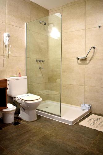 a bathroom with a toilet and a glass shower at Alamo Hotel in Villa Carlos Paz