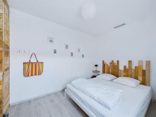a white bedroom with a bed and a purse on the wall at St Hilaire de Riez, Maison de ville pour 6 in Saint-Hilaire-de-Riez