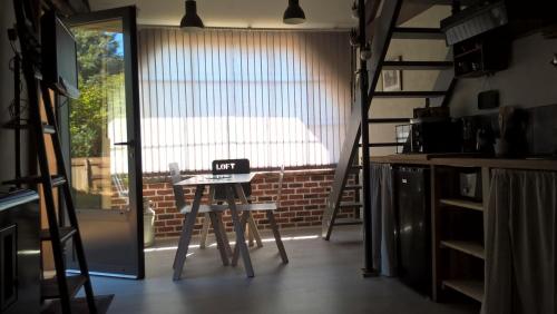 a room with a table and a ladder and a window at La Maréchalerie L'ATELIER in Lion-en-Sullias