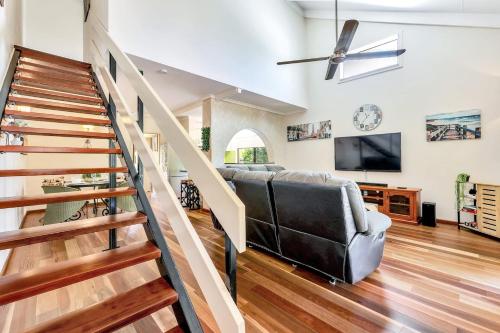a living room with a staircase and a couch at Tranquil Townhouse Huge Pool & Golf Course Views in Casuarina
