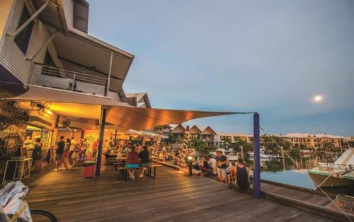 a group of people sitting on a deck near the water at Marina Views Cozy 3br Villa In Tipperary Waters in Stuart Park