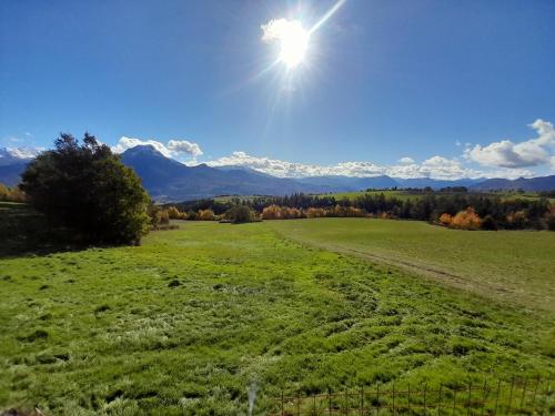 a green field with the sun in the sky at Le refuge des Toupins in Prunières