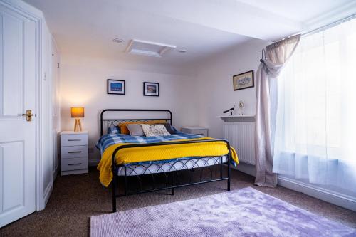 a bedroom with a bed with a yellow blanket at Coastal Terrace Retreat- Allocated Parking, 2 Bedrooms in Portsmouth