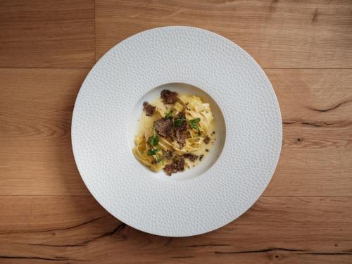 a white plate with food on a wooden table at Relais & Chateaux Schönegg in Zermatt
