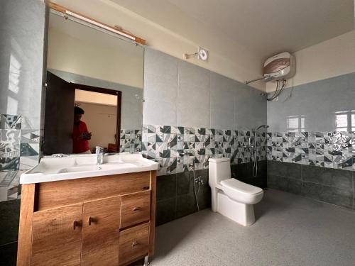 a bathroom with a sink and a toilet and a mirror at Hotel Monkhem Tawang in Tawang