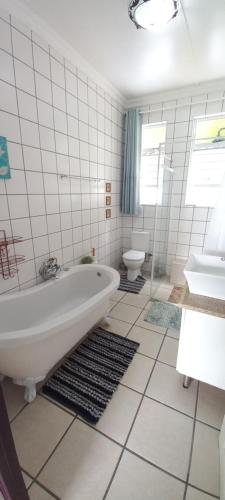 a white bathroom with a tub and a toilet at Opstal Herberg in Bredasdorp