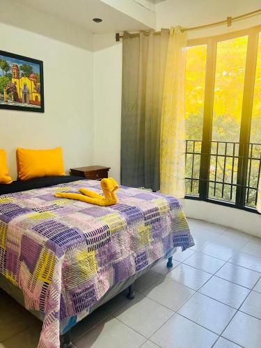 a bedroom with a bed with a purple and yellow blanket at Hotel Luna in San Marcos La Laguna