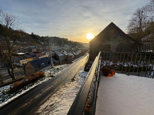 a winter scene with the sun setting behind a building at Apartmány za Královskou mincovnou in Jáchymov