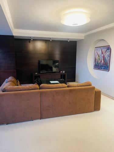 a living room with a brown couch and a television at Panoramic city center apartment in Klaipėda