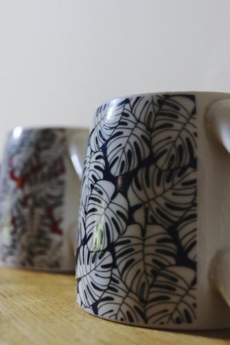 a black and white mug sitting on a table at Away with the Fairies Nature Lodge and Backpackers in Hogsback