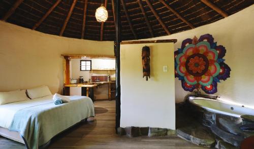 a bedroom with a bed and a tub in a room at Away with the Fairies Nature Lodge and Backpackers in Hogsback