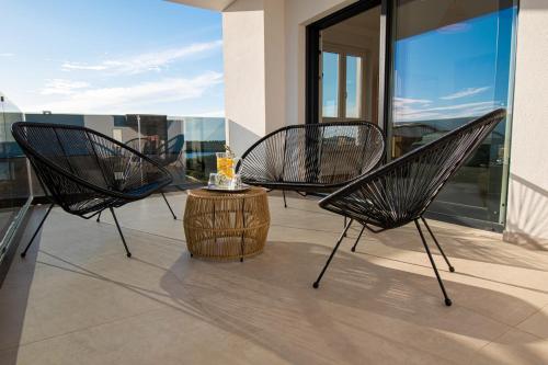 a patio with three chairs and a table on a balcony at Villa Ajlin mit privatem beheizbarem Pool in Medulin