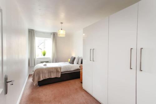 a bedroom with a bed and a window and white cabinets at Snowberry Close - Contractors Long Stay by ShortStayUK in Bristol
