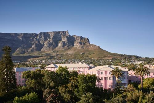 a pink building with a mountain in the background at Mount Nelson, A Belmond Hotel, Cape Town in Cape Town