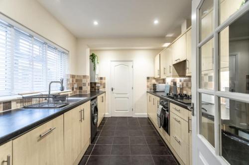 duża kuchnia z drewnianymi szafkami i zlewem w obiekcie Deacon Street-3 Bedroom, Sleeps 7, Long Stay Disc, Parking w mieście Swindon