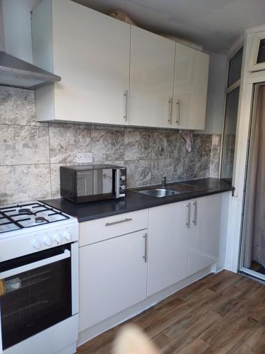 a kitchen with white cabinets and a microwave at Studio Apartment in London in Edmonton