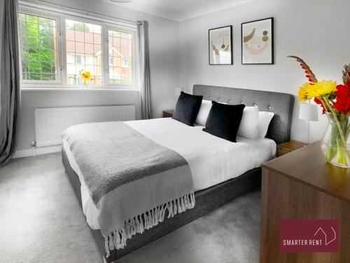 a bedroom with a large bed and two windows at Knaphill - 2 Bed House - Private Garden & Parking in Brookwood